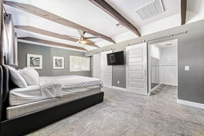 Un dormitorio con cama, televisor, armario y ventilador de techo.