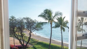 A beach view with palm trees and a clear sky.