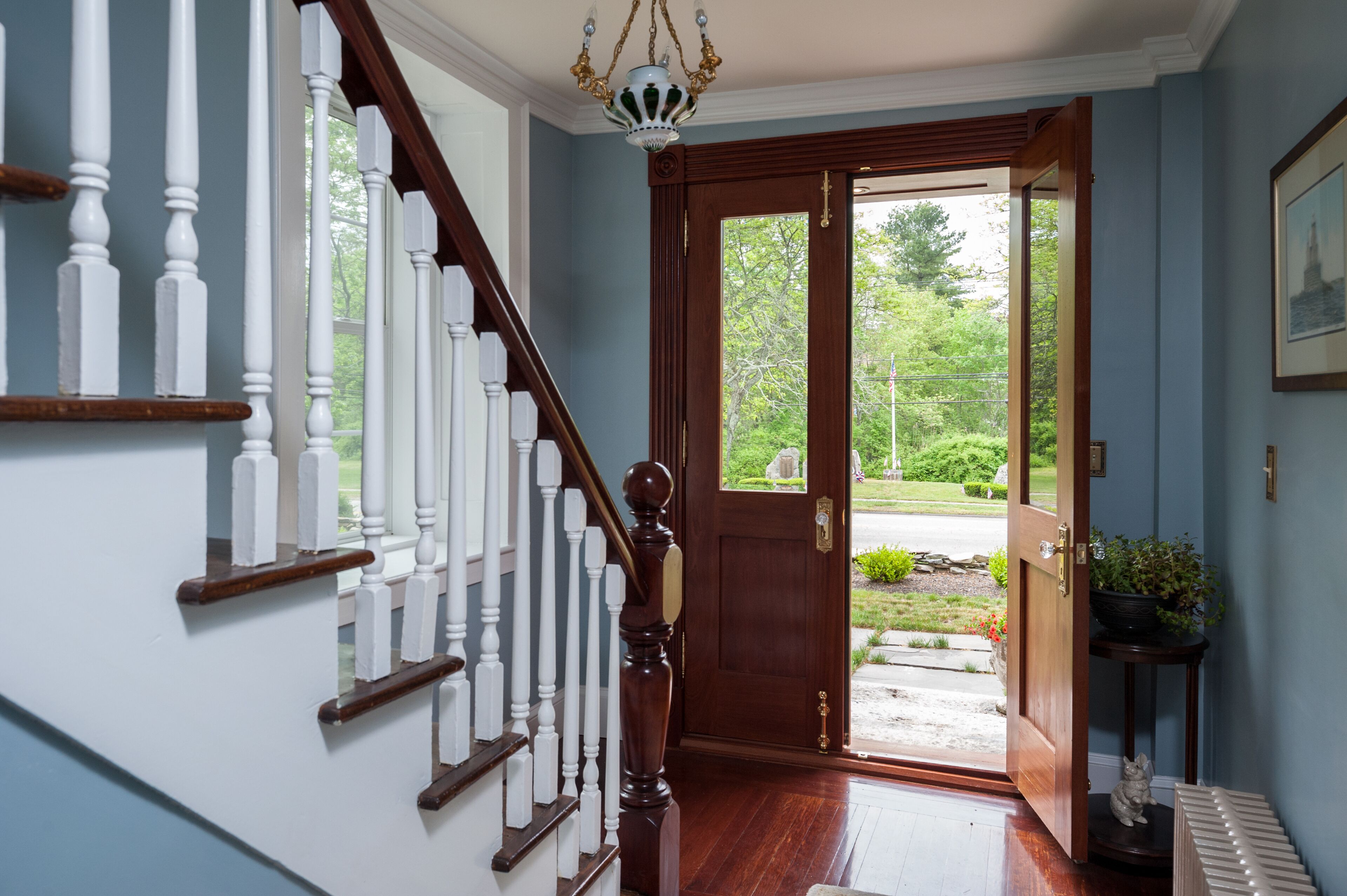 Un escalier en bois, avec des balustrades blanches, mène à une porte dotée d’un panneau de verre.