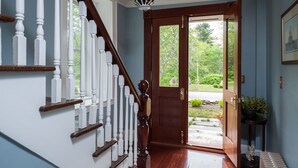 A wooden staircase with white balusters leading to a door with a glass panel. - A Historic Place to Stay for Your Historic Days. Gracious Granite Home + Tavern (Waterford)