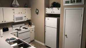A kitchen with white cabinets, a microwave, stove, sink, and a refrigerator.
