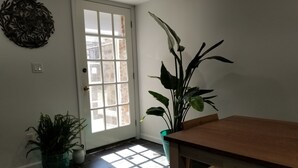 A room with a wooden table, a potted plant, and a door with a view to the outside. - Elegant NYC Pad with Wifi (Queens)