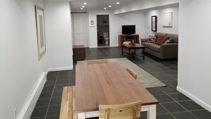 A modern living room with a wooden dining table, a sofa, and a television. - Elegant NYC Pad with Wifi (Queens)