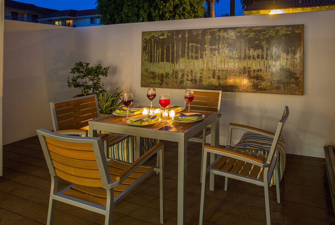 Un coin repas avec une table dressée pour quatre personnes, entourée de chaises, et un tableau accroché au mur.