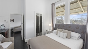 A bedroom with a large bed, a bedside table with a lamp, a chair, a wardrobe, and a shower area. - Healesville Garden Accommodation “GRANDVIEW”   (HEALESVILLE)