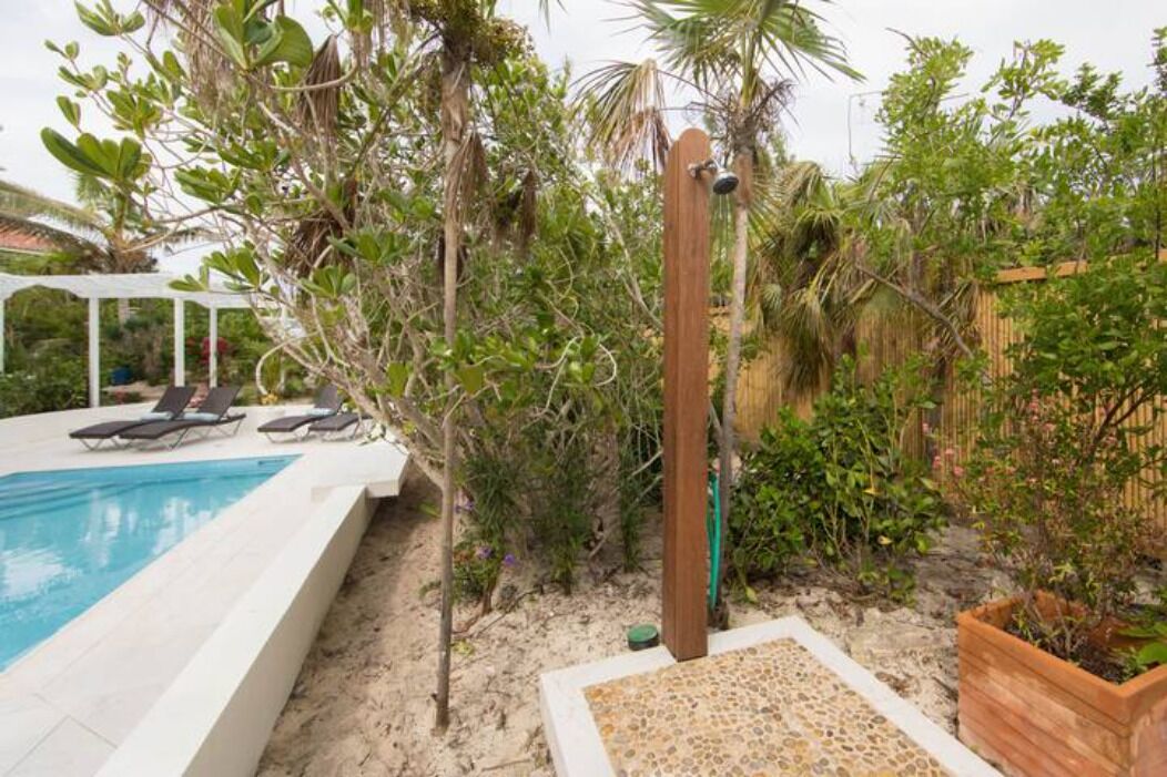 A pool area with lounge chairs, a wooden post, and surrounding vegetation.