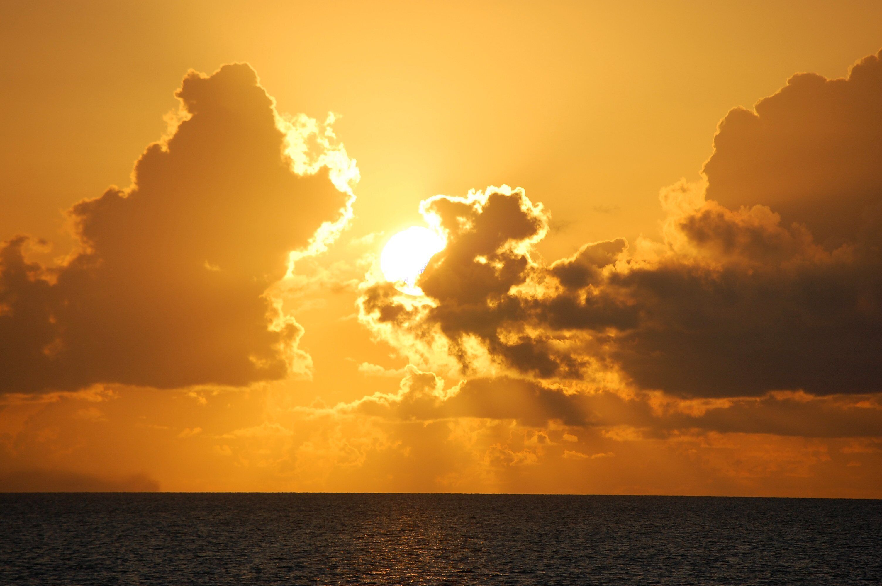 Un coucher de soleil sur l’océan, avec des nuages.
