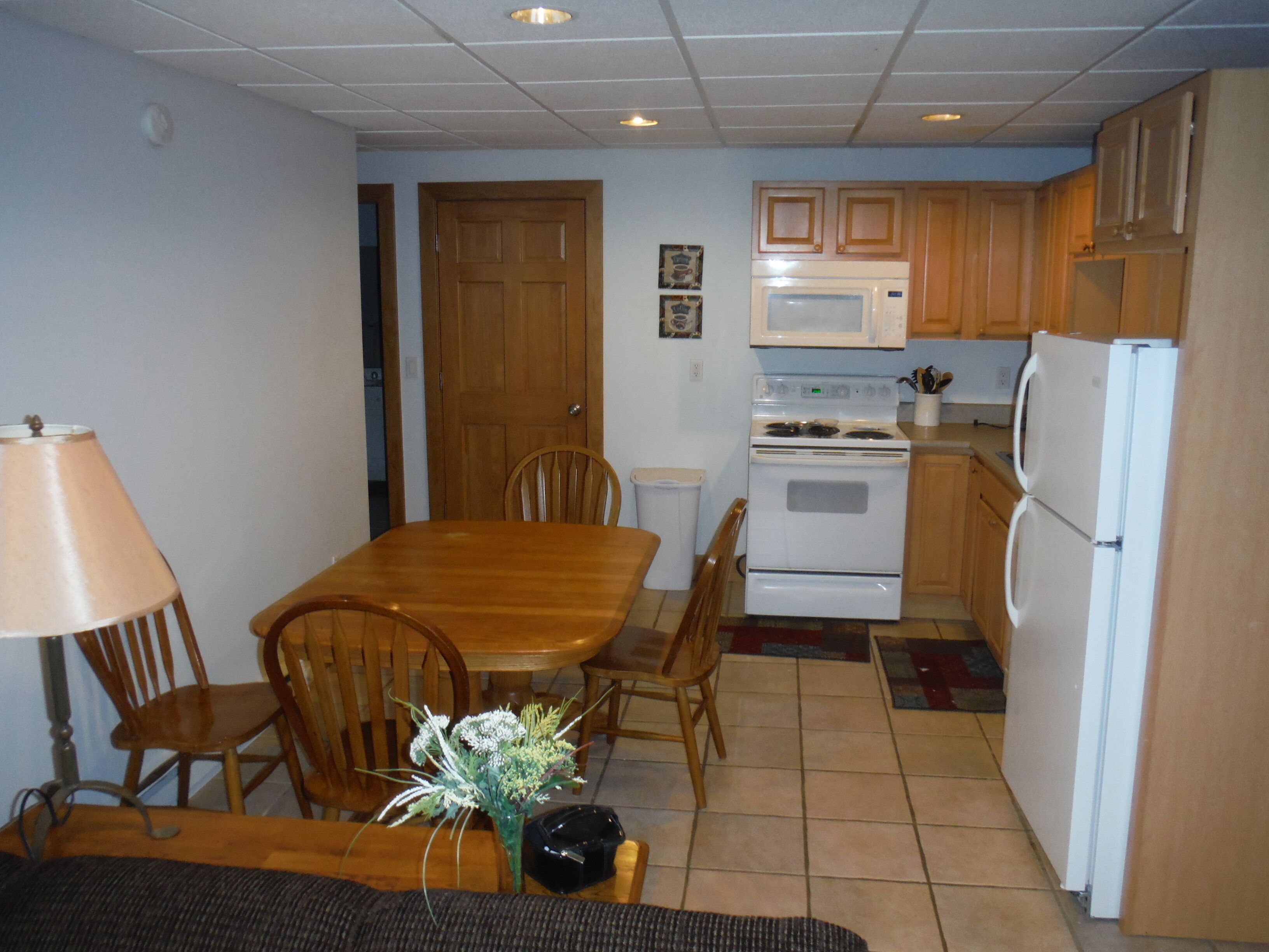 A compact kitchen with wooden cabinets, a white stove, and a refrigerator.