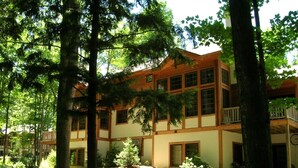 A two-story building with a wooden exterior and multiple windows, surrounded by trees and greenery. - Boyne Mountain on Resort Condo, close to Lifts, Lodge, Waterpark, all amenities (Boyne Falls)