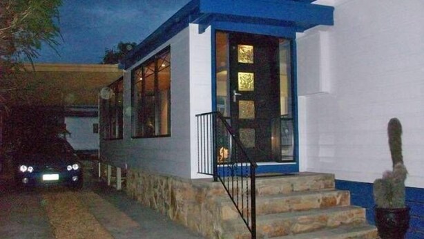 A two-story house with a stone staircase leading to the front door, which has a black metal railing. - Entrance to the Lakes Getaway (Lakes Entrance)