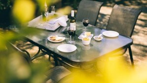 A dining table set outdoors with plates, glasses, and a bottle of wine. - Lexington Park Cottage (Cambridge)