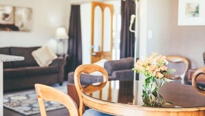 A dining area with a round table, chairs, and a vase of flowers. - Lexington Park Cottage (Cambridge)