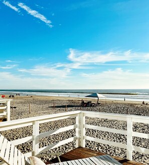 A wooden deck with a view of a beach and ocean.