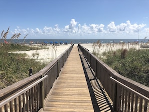 Walk along the beachside boardwalk, flanked by sandy dunes and lush vegetation.