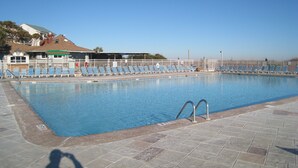 Ein Schwimmbad mit Liegestühlen und einem Rettungsschwimmerstand.