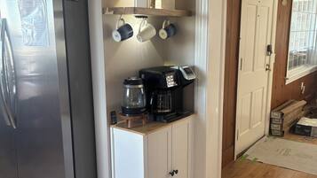 Une cuisine équipée d’un réfrigérateur en acier inoxydable, d’une machine à café et d’un meuble en bois.