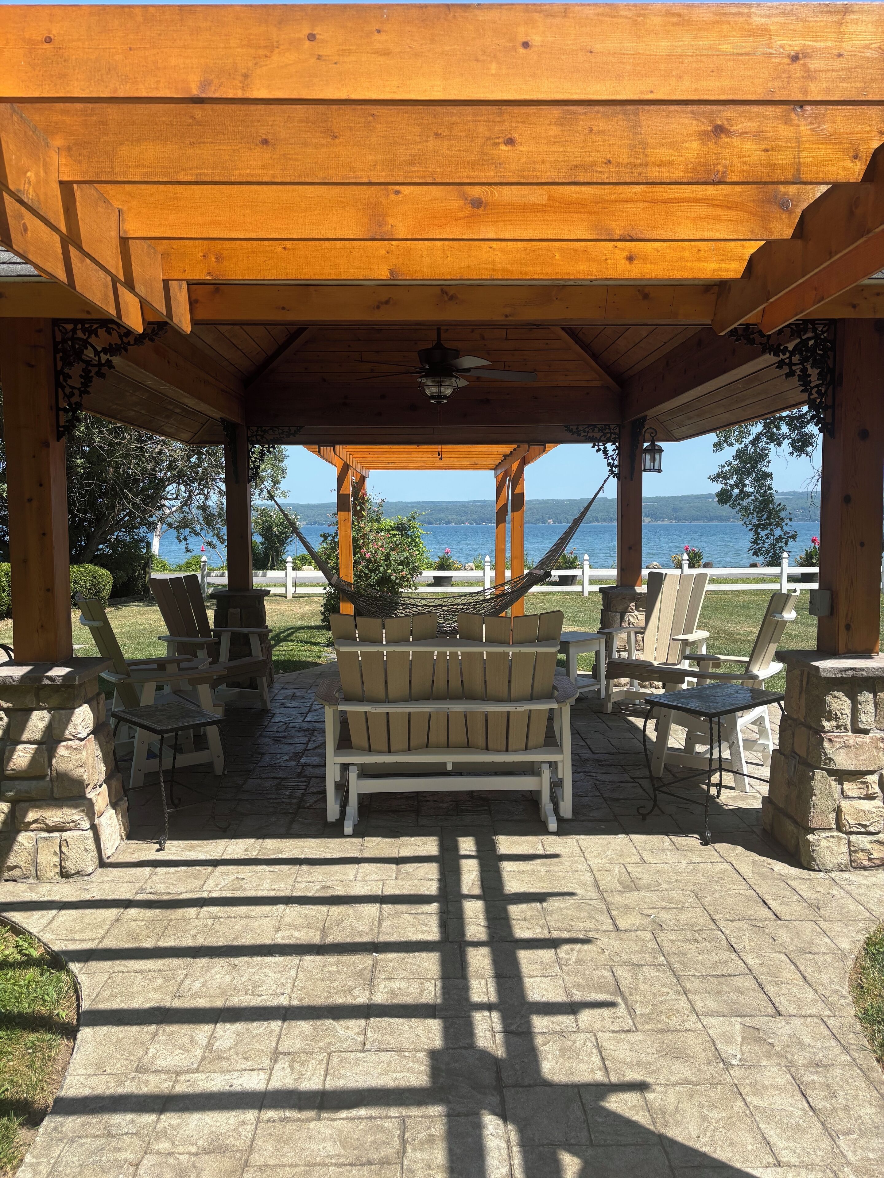 An outdoor patio with a wooden pergola, a hammock, and outdoor furniture.