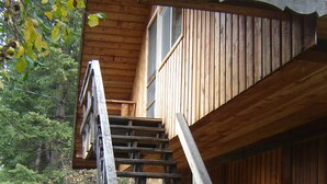 A wooden staircase leading to a cabin with a sloped roof, surrounded by trees and a fence. - Martins Vacation Rental (Hungry Horse)