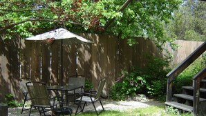 A patio with a table and chairs, a wooden fence, and a staircase. - Martins Vacation Rental (Hungry Horse)