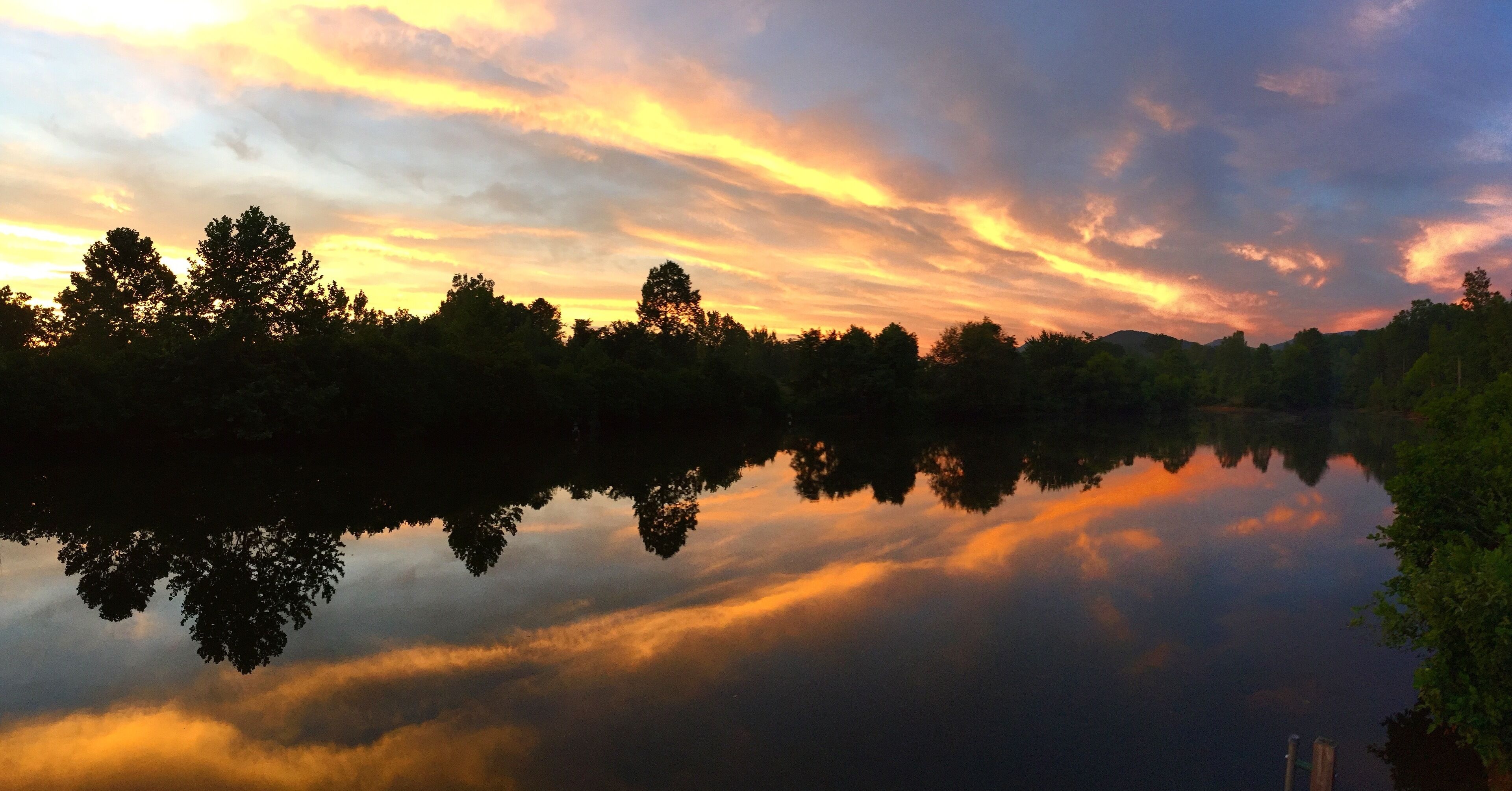 Un lago tranquilo reflejando árboles y un cielo al atardecer.