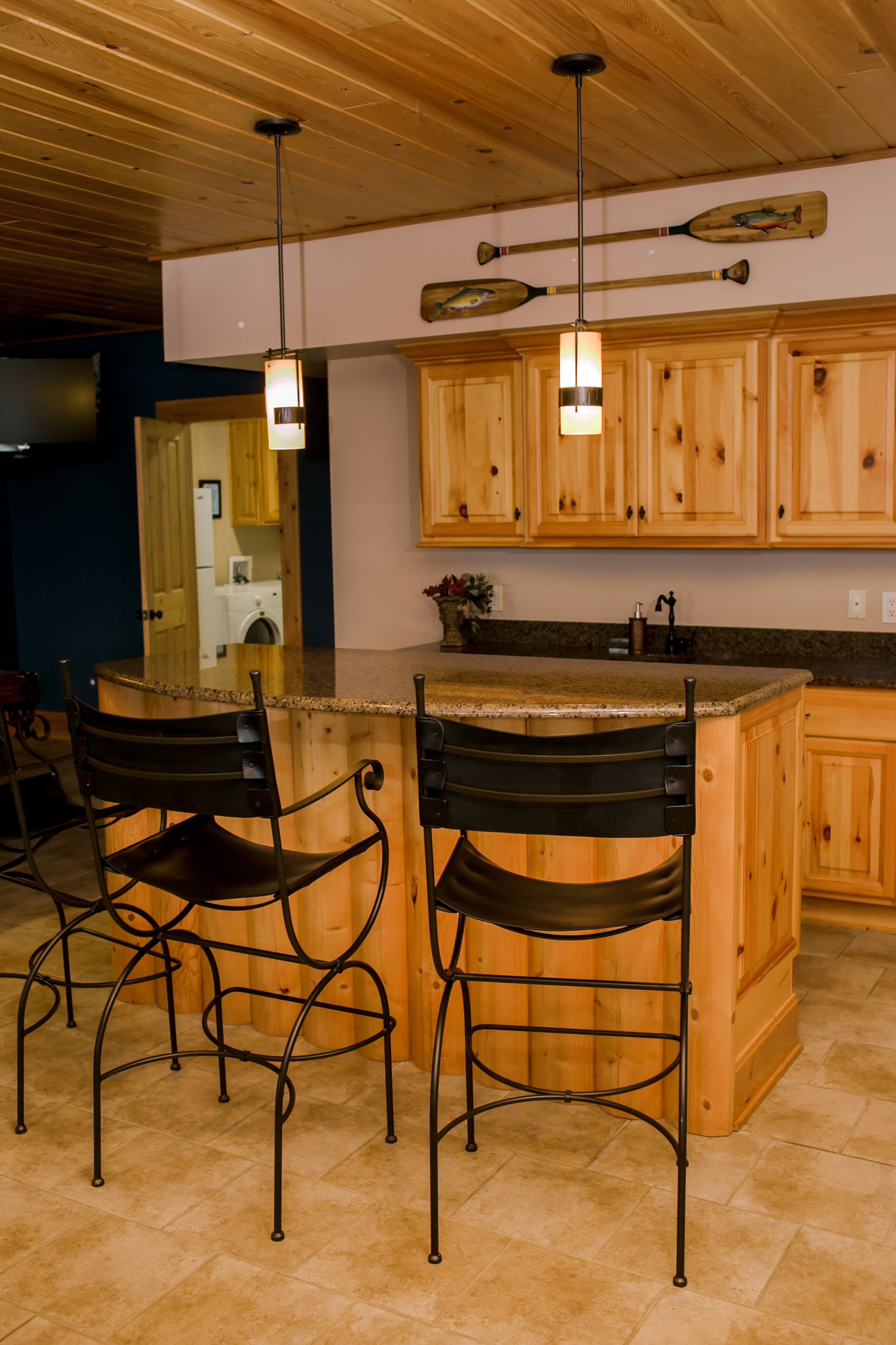Una cocina con armarios de madera, encimera de granito y una barra con sillas de metal.