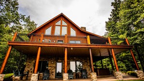 A lodge with a stone facade, wooden balcony, and outdoor seating area.