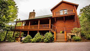 A log cabin with a balcony and a stone chimney.