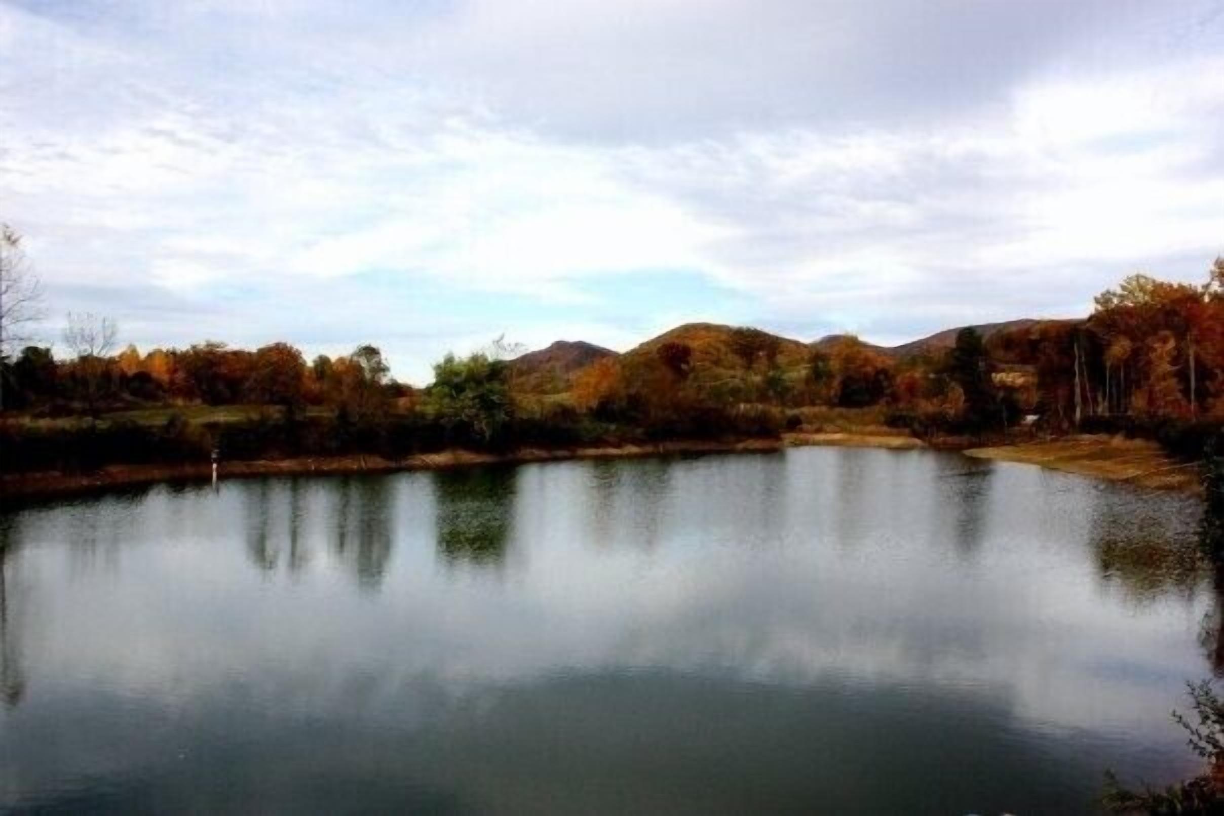 A calm lake with reflections of trees and hills.