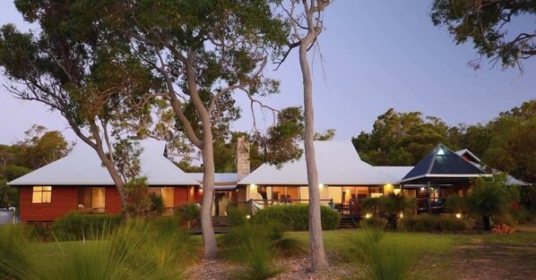 A property with multiple buildings, including a main house and a smaller structure, surrounded by trees and grass.