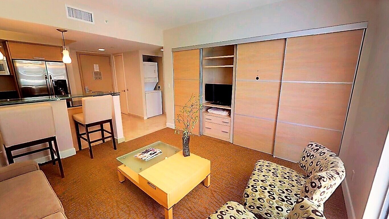 Un espacio habitable compacto con kitchenette, un sofá, una mesa de centro y un televisor.