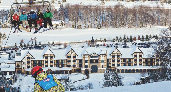 A ski resort with a large lodge featuring a symmetrical facade, multiple windows, and a central entrance.