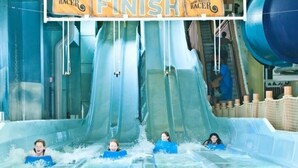 Un toboggan aquatique avec plusieurs pistes et un panneau indiquant « Arrivée » à la fin.