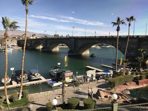 A bridge over a river with boats docked, palm trees, and a sign indicating a restaurant is open. - Spread Out with Family and Friends with 2 Living Rooms! (Lake Havasu City)