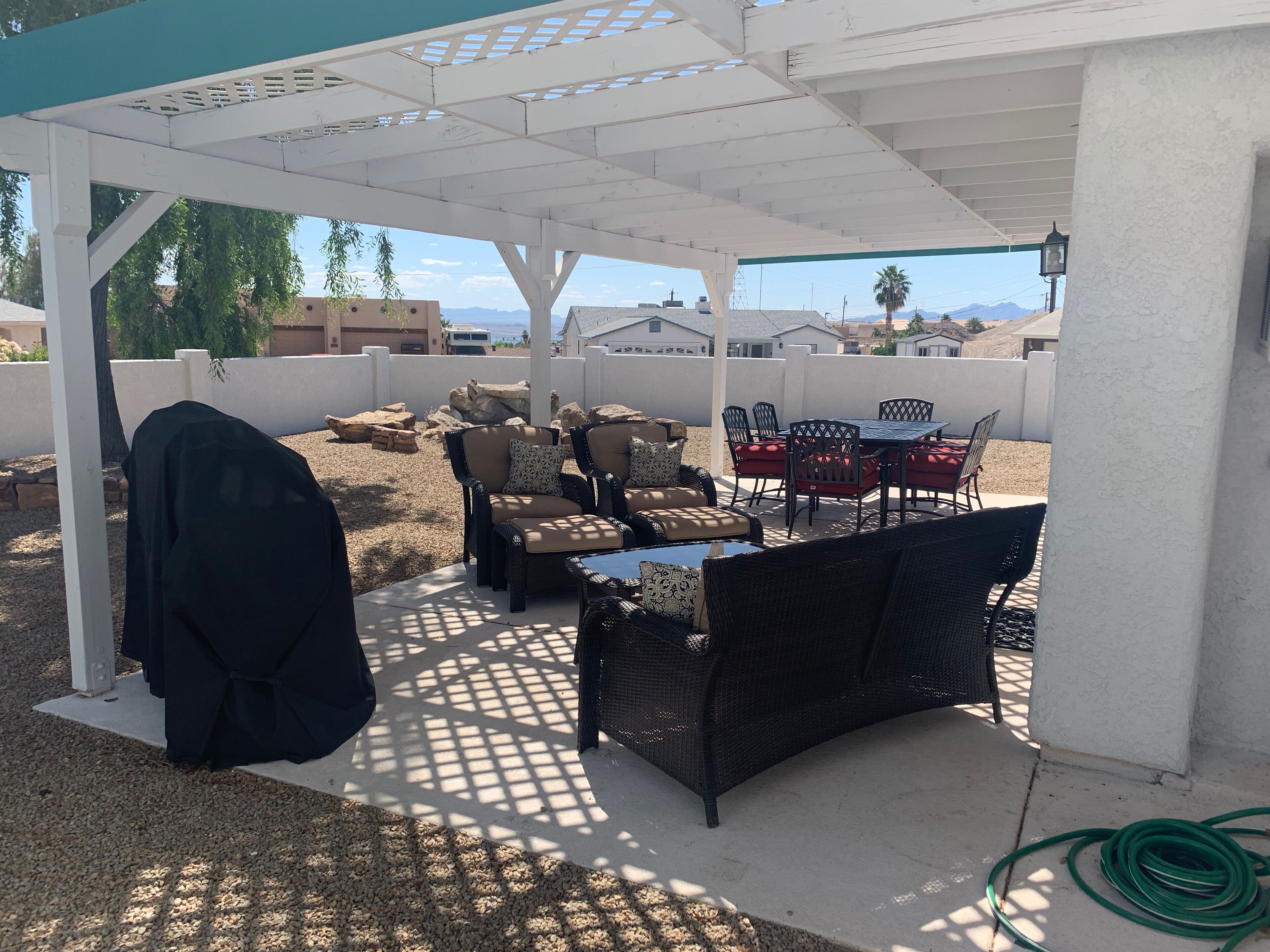 Een terras buiten met rieten meubels, een tafel en stoelen.