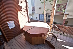 A hot tub on a wooden deck with a metal railing, surrounded by a wooden fence and trees. - Penthouse By The Gondola - Ore Station Lodge (Telluride)
