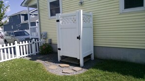 A white wooden gate with a lattice design, a white picket fence, and a car parked in the driveway.