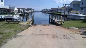 A marina with boats docked, a pedestrian walkway, and houses in the background.
