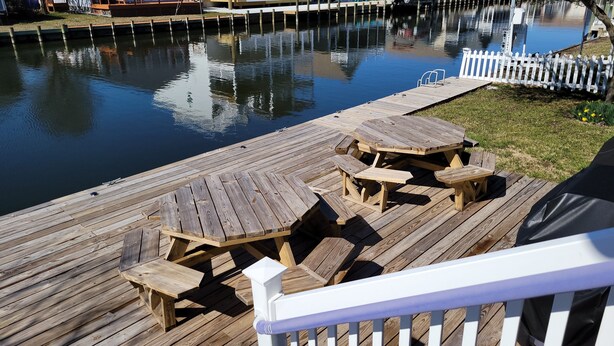 A wooden deck with picnic tables and a white railing.