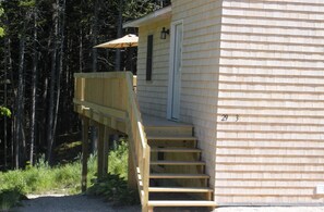 Une cabane en bois avec un escalier en bois menant à une porte, le tout entouré d’arbres.