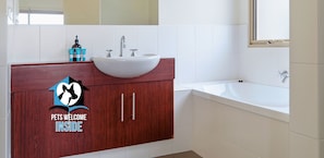 A bathroom with a white sink, a mirror, a wooden vanity, and a bathtub. - 24/45 St. Andrews Blvd, Normanville - Contemporary Golf Course Frontage 3BR (Normanville)