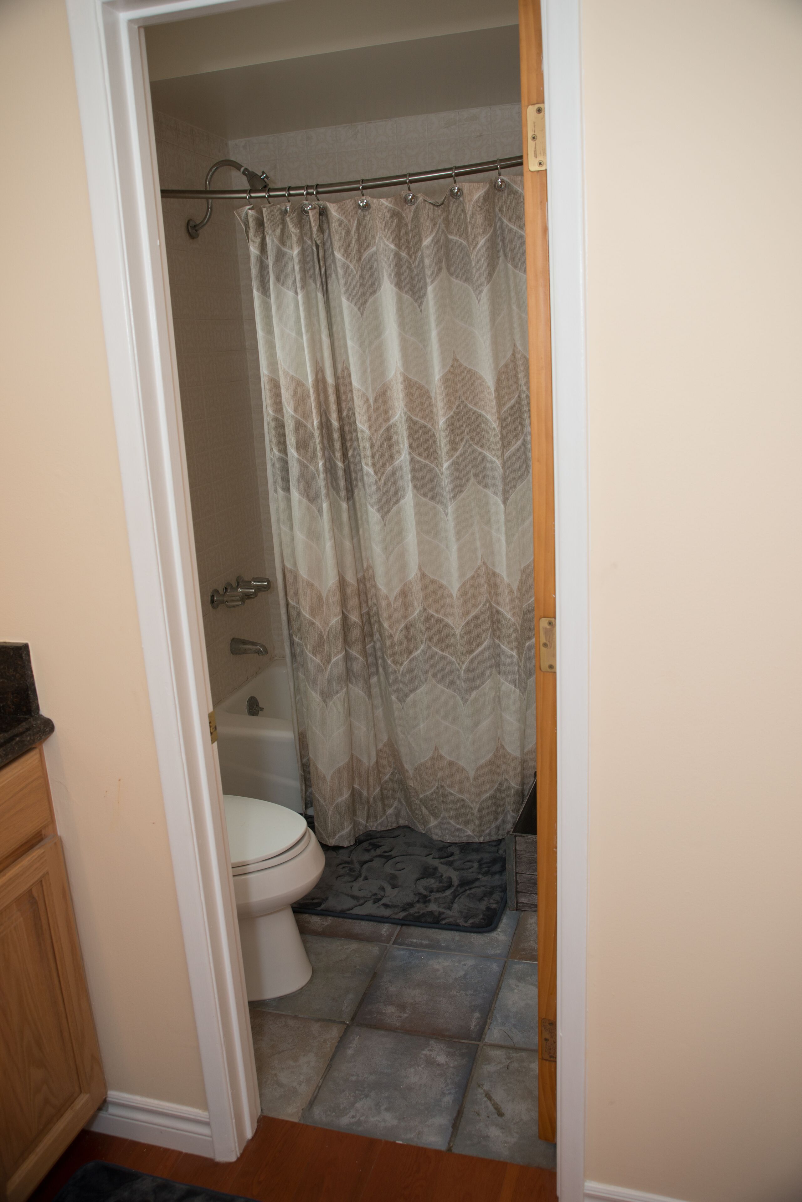 Een badkamer met toilet, douchegordijn en betegelde vloer.