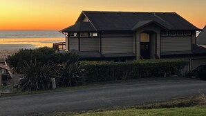A two-story house with a balcony, located near a beach with a sunset view. - Oceanfront Beach House-Nestled on the N. Beach of the Washington Coast (Moclips)