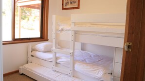 Habitació amb literes, una finestra, una porta i un quadre al mur.