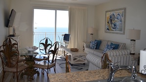 Ein Zimmer mit Esstisch, Stühlen, einer Couch, einem Fernseher und Meerblick.