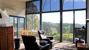 Relax in a spacious living area with a sofa, chairs, and TV, offering a panoramic view of the surrounding landscape.