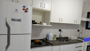 Eine Küche mit weißen Schränken, einem Kühlschrank, einer Spüle und einem Herd.