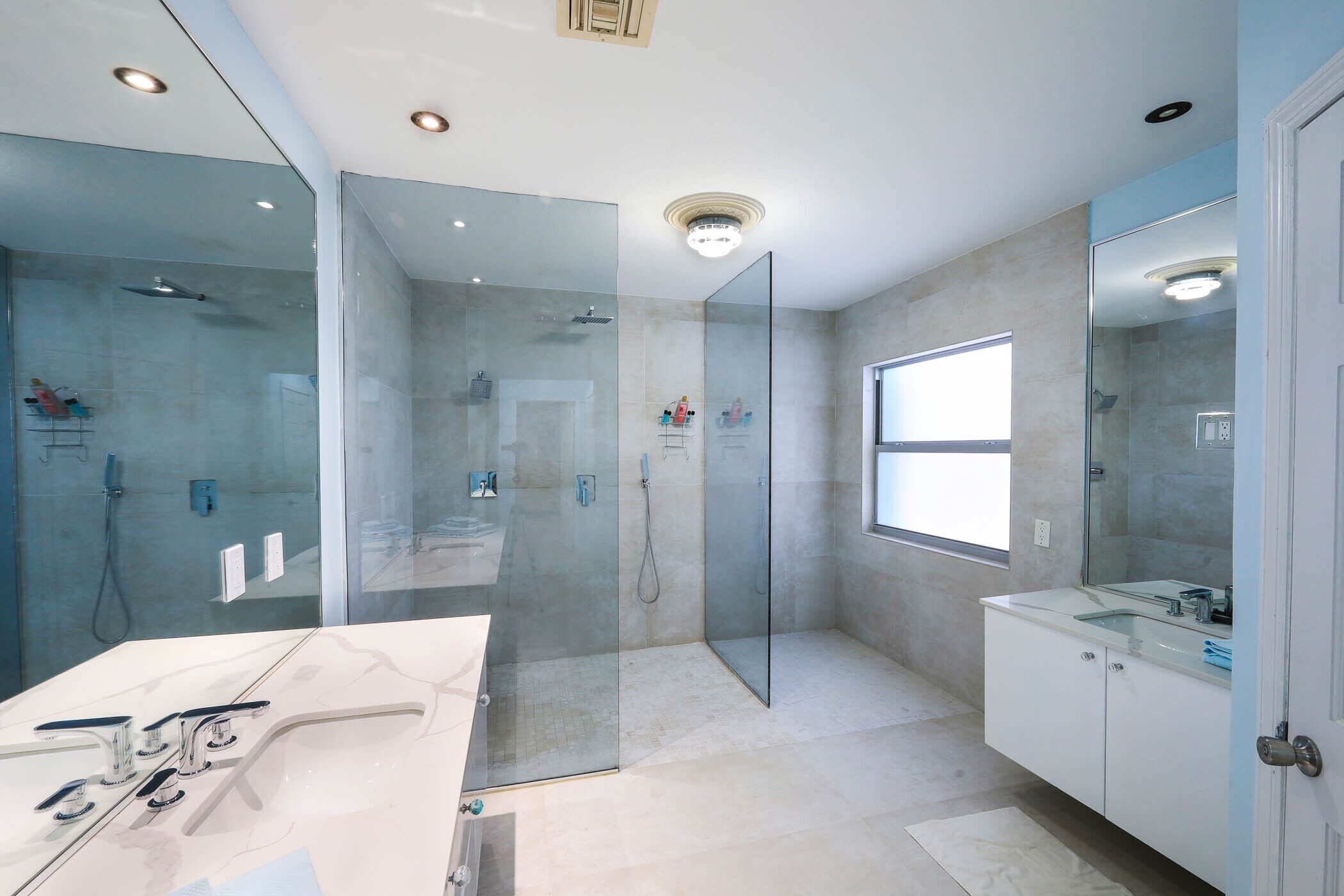 A modern bathroom with a glass-enclosed shower, a vanity with a sink, and a large mirror.
