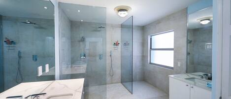 A modern bathroom with a glass-enclosed shower, a vanity with a sink, and a large mirror.