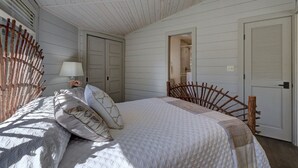 Um quarto com uma cama, mesa de cabeceira, luminária e uma cadeira de madeira.
