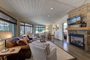 A spacious living room with a fireplace, comfortable seating, and a television mounted on the wall.